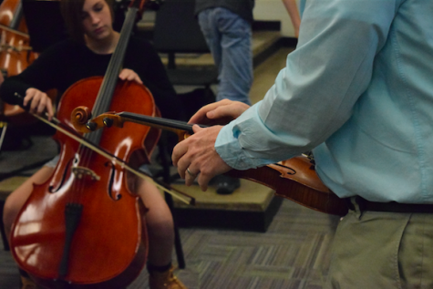 Welch helps a freshman tune her violin.