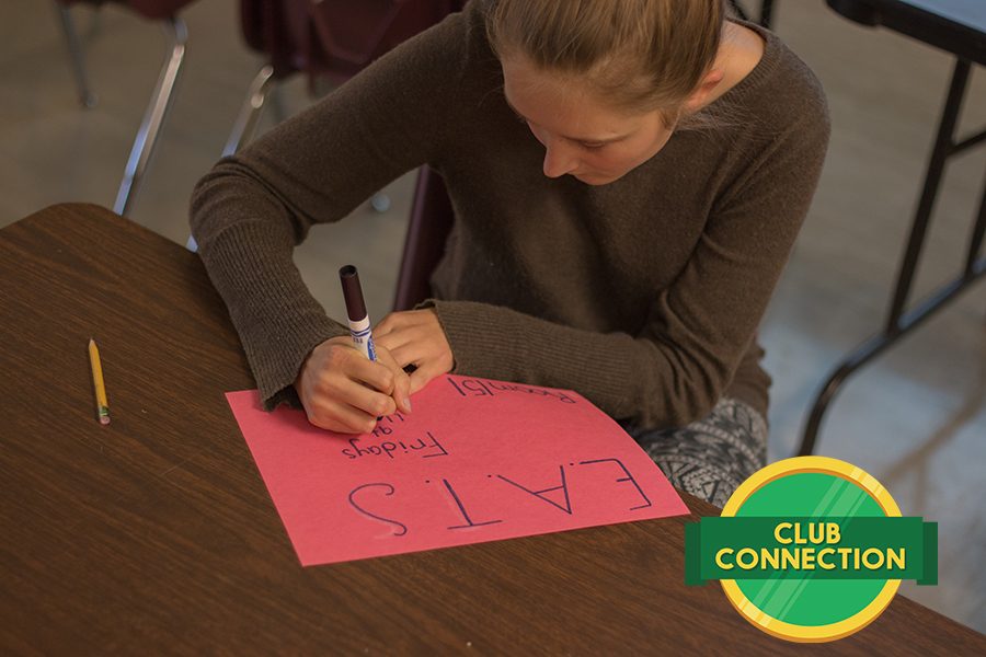 Club leader Mara Jensen creates posters to hang around the school advertising the club.
