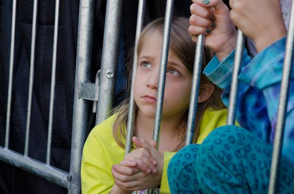 Transfixed on Sen. Sanders, a young girl clasps her hands together after cheering from the makeshift nook she made at the base of a crowd divider.