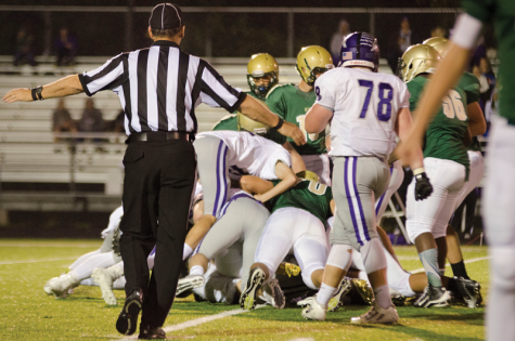 A football official breaks up a dog pile during the West-Burlington game