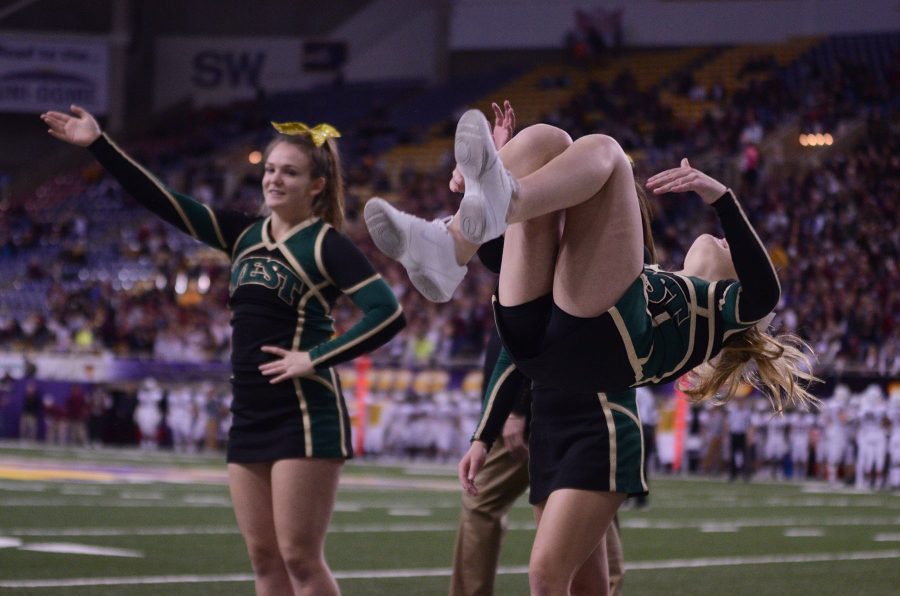 The cheerleading team goes down the line each performing a backflip.