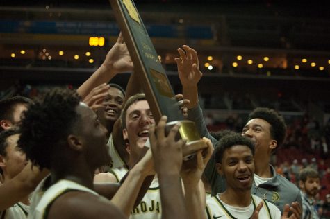 The varsity boys basketball team celebrates after receiving the 4A state championship trophy Saturday Mar. 11 at Wells Fargo Arena. After a loss to West Des Moines Valley in last years championship game, the Trojans avenged their loss this year in a 64-50 victory for the teams seventh state title. 