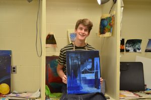 Micah Smith 17 holding one of his newer abstract pieces of art.
