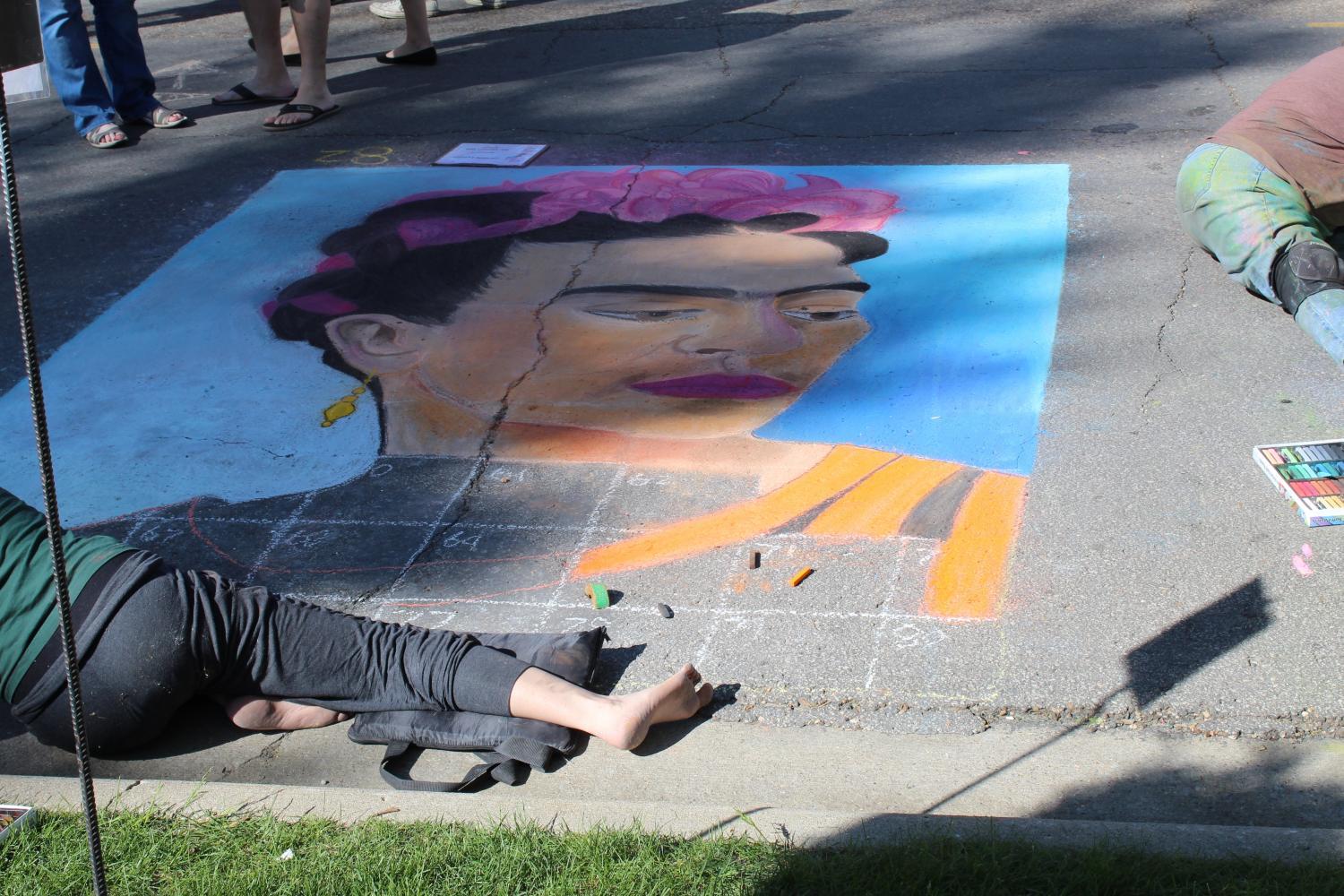 An artist works on her chalk art piece of Frida Kahlo. Artists were given chalk and an 8’ by 10’ section to work on.