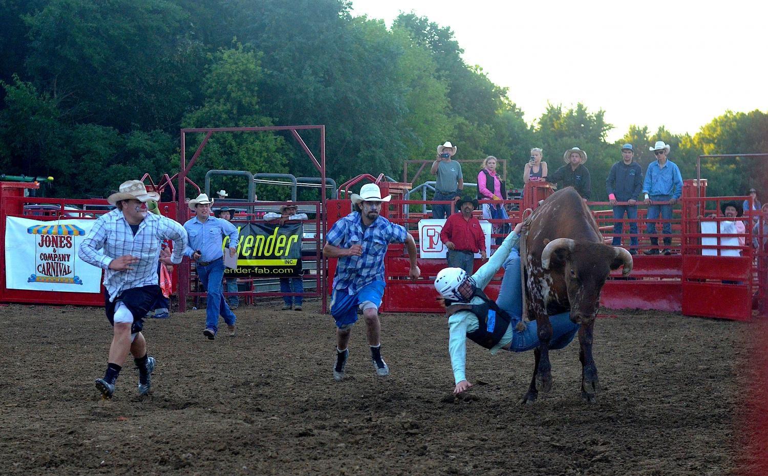 Rodeo assistants run to aid a fallen bullrider during the Johnson County Fair in Iowa City on July 27.