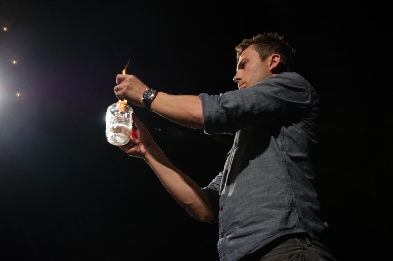 Nate Staniforth sets a dollar bill on fire as a part of his performance at the Englert Theatre on Sept. 11 for the Green Room.