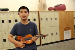 Justin Liu 19 displays his violin in the West High orchestra room