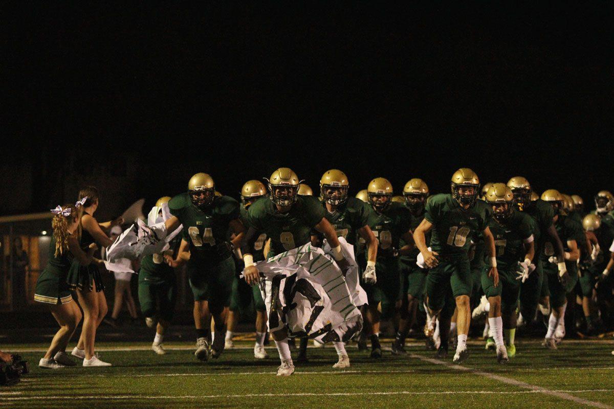 The Trojans take the field by ripping through a poster on Friday, Sep. 22.