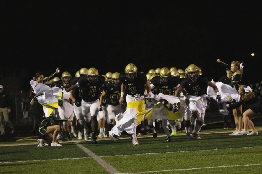 The Trojans run through an For the Kids (FTK) banner as they take the field on Friday, Oct. 6.