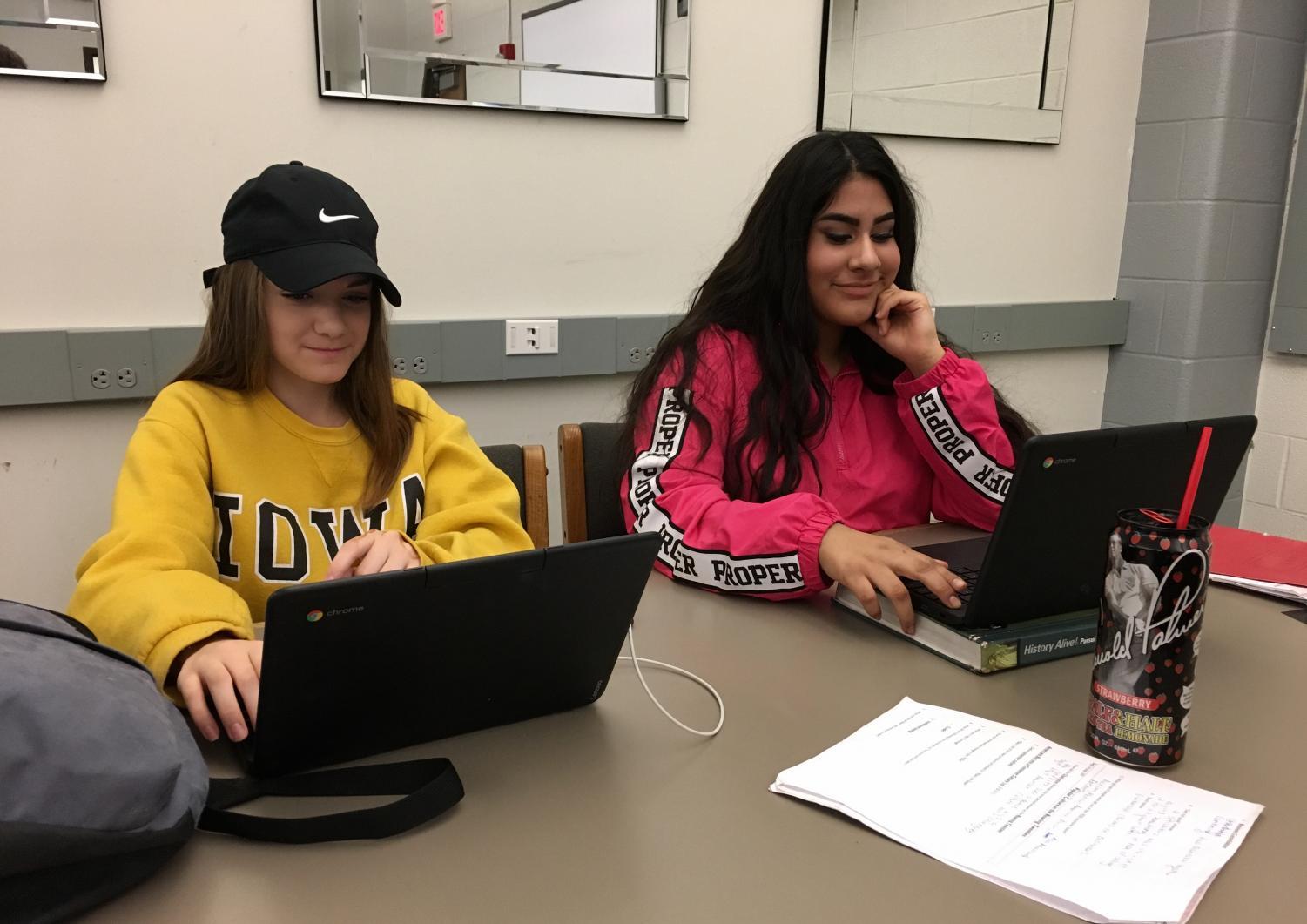 Courtney Mapel '21 and Lizette Perez '21 restart their Chromebooks after an accidental update by the district forced students to login every time they shut their laptop.