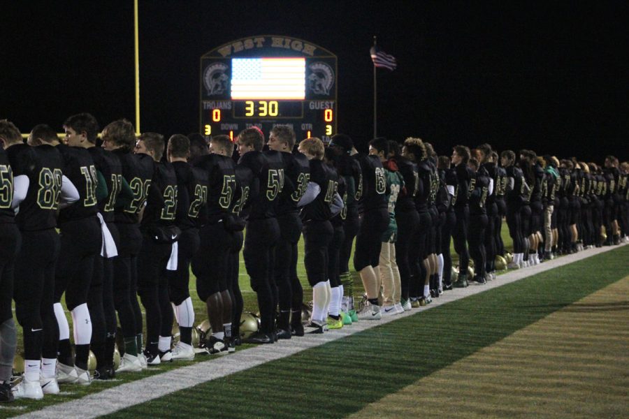 The football team stands together during the National Anthem on Friday, Oct. 27.