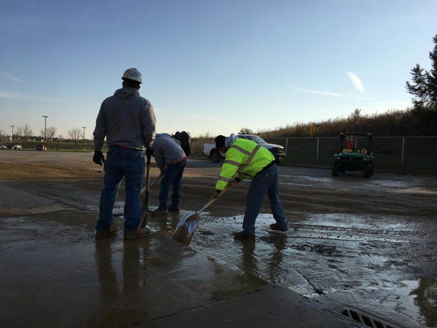 Construction workers scrape remaining water into nearby sewage drains.