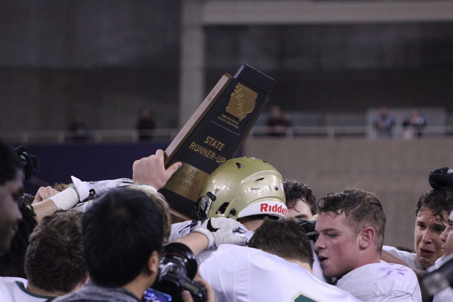 Dillon Doyle 18 lifts the state runner-up trophy up as the team gathers around it on Friday, Nov. 17.