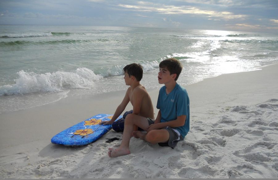 Aiden and Orion sit on the beach in Seaside, Florida listening to the waves.