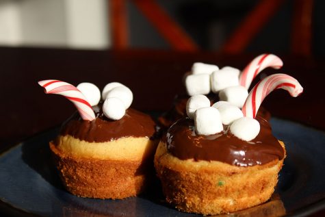 The completed muffins have been dipped into melted chocolate and decorated with mini marshmallows and candy canes.