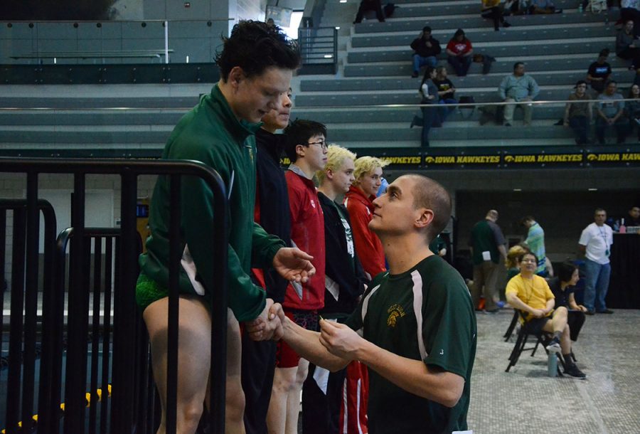 Izaak Hajek 20 receives a medal from West Highs swimming coach Byron Butler for placing first in the 100 fly.