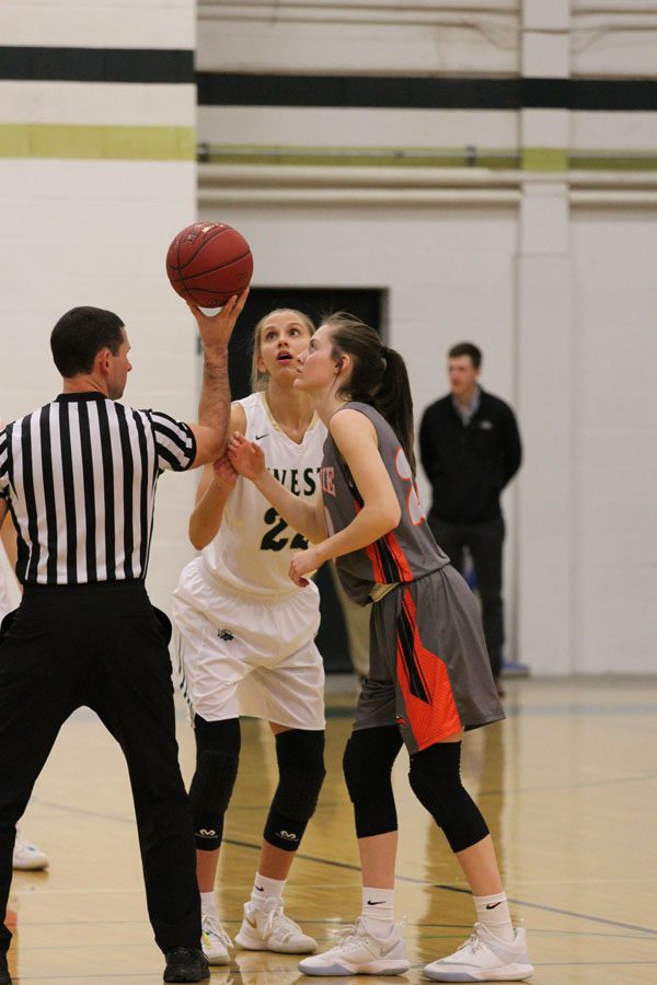 The referee holds the basketball up in preparation for tip off, while Logan Cook '18 concentrates on the ball on Friday, Jan. 19.