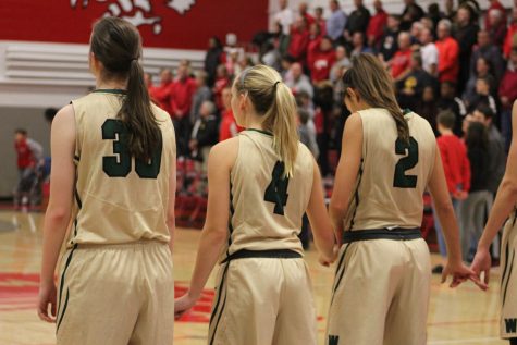 Paige Beckner 18, Lauren Zacharias 19 and Cailyn Morgan 19 hold hands together during the national anthem on Tuesday, Dec. 12.