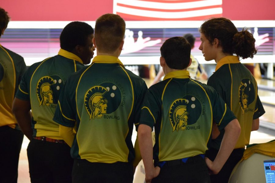 The boys bowling team huddles together and talks about their bowling strategies.