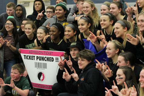 The student section and the girls basketball team poses in front of the state qualifier banner on Tuesday, Feb. 20.