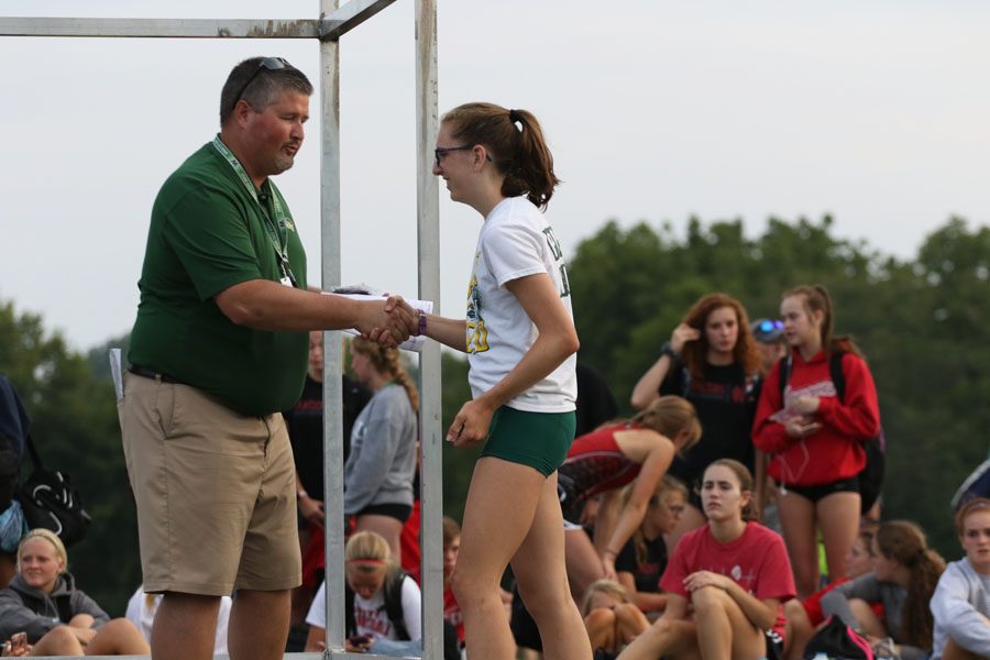 Erica Buettner '21 shakes hands with West High Athletic Director, Craig Huegel as she receives an award for 9th place.