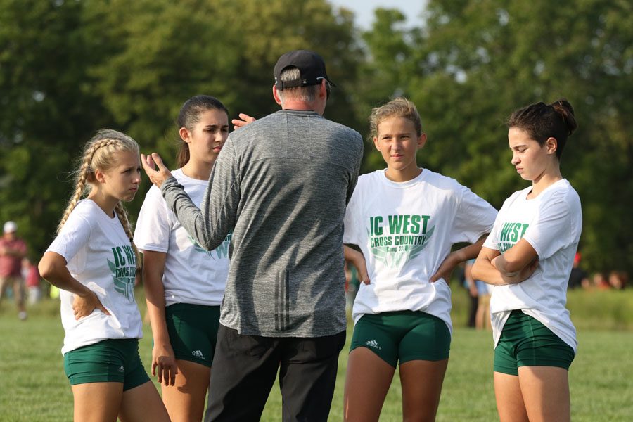 Coach Mike Parker prepares sophomores Maddy Negley, Anna Moore, Lucy Westemeyer and Kiara Malloy-Salgado before the varsity race on Thursday, Aug. 23.