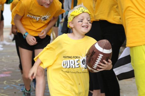 Kid captain Otto Phelps runs a football through a tunnel at the tailgate on Friday, Sept. 21.