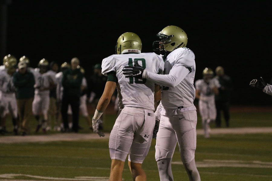 Ramey Fahal '19 pats Cole Mabry '19 on the back after Mabry tackled a player from Linn-Mar during the first half on Friday, Sept. 28.