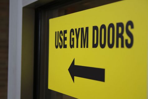 A sign telling visitors to use the gym doors hangs on a door leading to the commons on Tuesday, Oct. 2.