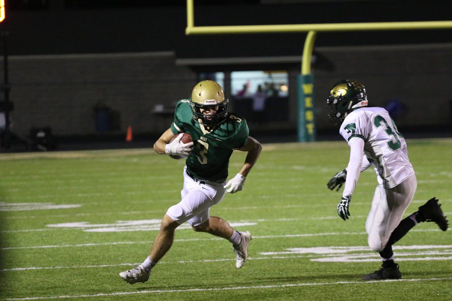 Justin Thomas '19 carries the ball down the field as Cedar Rapids Kennedy's CJ Currie '20 runs towards him on Friday, Oct. 26.