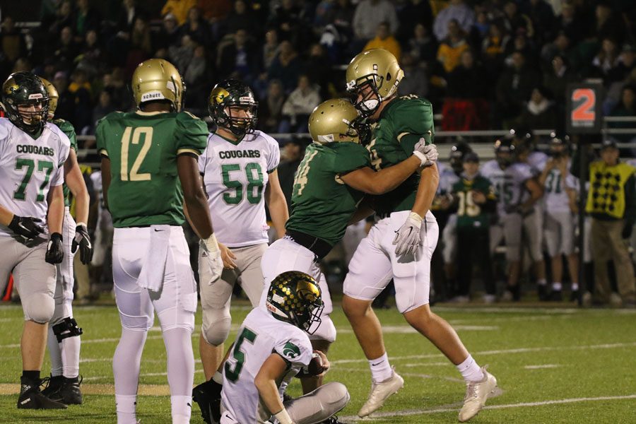 Landon Green '19 and Owen McAreavy '19 celebrate after taking down Cedar Rapids Kennedy's Max White '21 during the first half on Friday, Oct. 26.