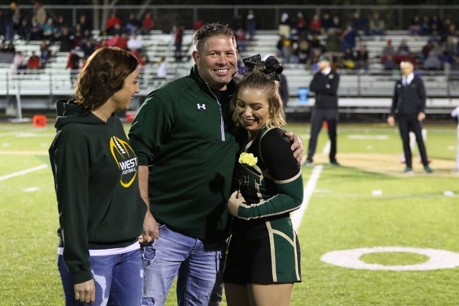 Lexi Goodale '19 stands with her parents as her name is called during the senior recognition ceremony before the game on Friday, Oct. 19.