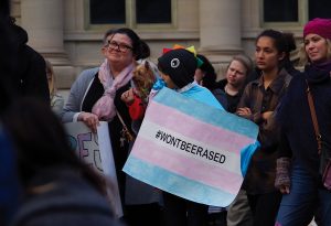 Community members hold signs in support of transgender rights at a “Support Trans Lives” rally at the Pentacrest Oct. 25, 2018.