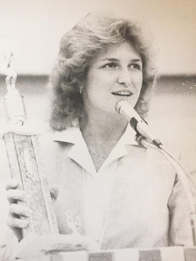 Sue Chelf speaks while holding a trophy during her time at West High.