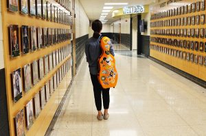 Perry Heredia 21 walks down the hallway with her viola on her back.