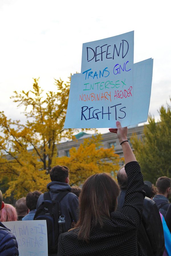 During a Support Trans Lives protest on the Pentacrest, a woman holds up a sign in support of transgender rights on Thursday, Oct. 25.