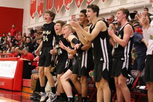 The Trojans bench erupts in cheers after Charlie Moreland 20 scores a three-pointer during the second half on Friday, Dec. 7.