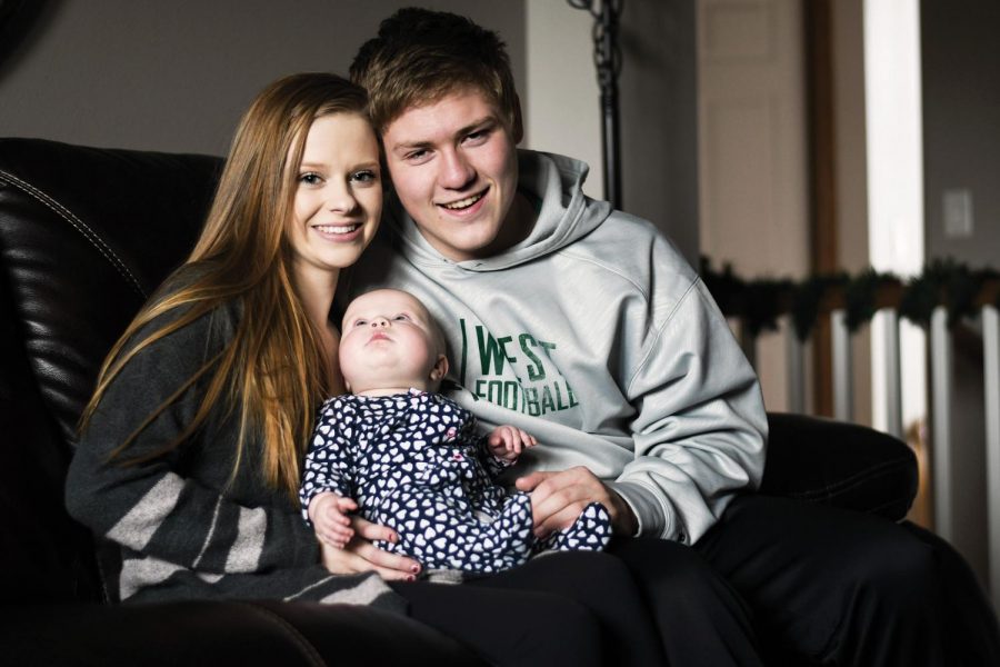 Sydney Johnston ’19 and Noah Breitbach ’19 hold their six-month-old daughter Stella Mae Breitbach while sitting in the living room in Sydney’s house.
