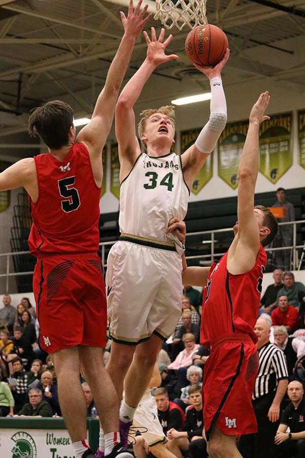 Even Brauns '20 scores two points for West as Linn-Mar's Jaren Nelson '19 and Hayden Passmore '19 try to block him during the first half on Friday, Jan. 4.