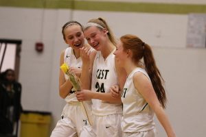 Emma Koch 19 sheds tears as she walks down the court with Audrey Koch 21 and Rylee Goodfellow 21 during the senior recognition after the game on Saturday, Feb. 16.