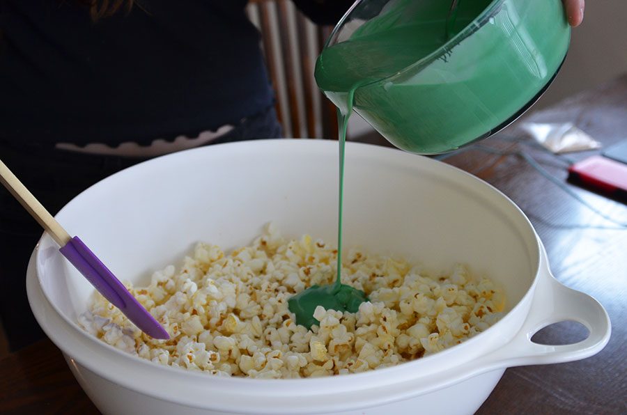 Melt a bag of green candy melts in the microwave and pour it over half of the popcorn. 