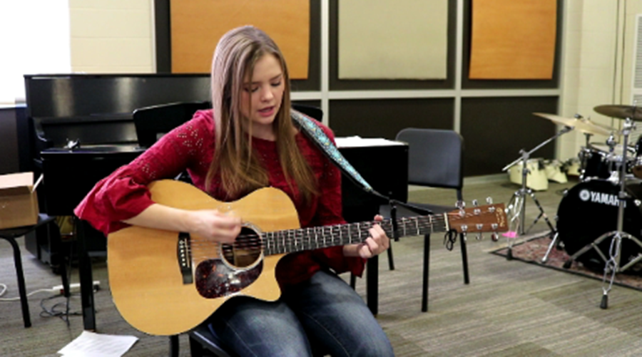 Abbie strums her guitar as she begins to sing her newly released single.