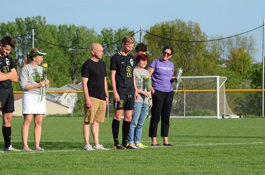 Joshua Jasek '19 stands with his parents while being honored by his coach.