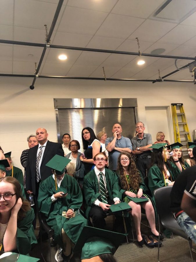 Students and Graduation-attendees crowd together closely monitoring the television for updates on the storm.