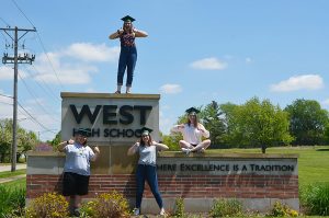 Kara Wagenknecht 19, Lucy Polyak 19, Maddi Shinall 19 and Sophie Stephens 19 pose at the West High sign outside of the school.