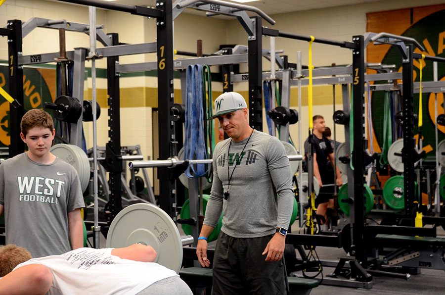 Coach Hartwig watches Joey Chase 21 as he gets ready to lift at football practice. 
