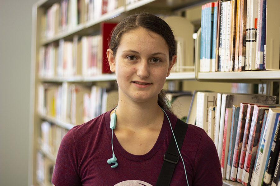 Renee Gould standing in front of a book shelf in the Iowa City West High library. 