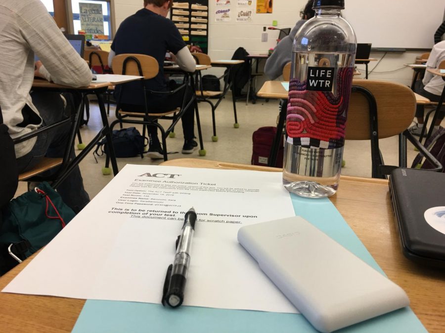A students desk sits ready for the ACT, equipped with a pencil, calculator and water bottle.