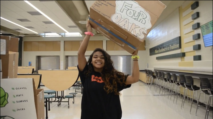 Sabrina Williams 22, iJAG Community Service Representative, poses with one of the donation boxes that can be found around West.