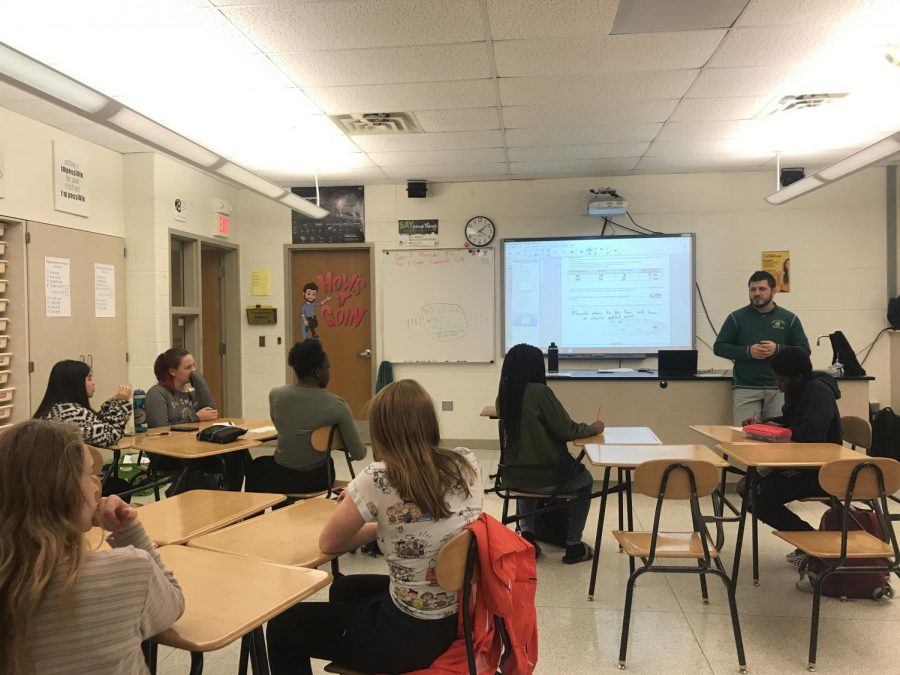 Assistant boys wrestling coach Kody Pudil speaks to a group of about 10 girls after school about uniforms, coaching and the season. 